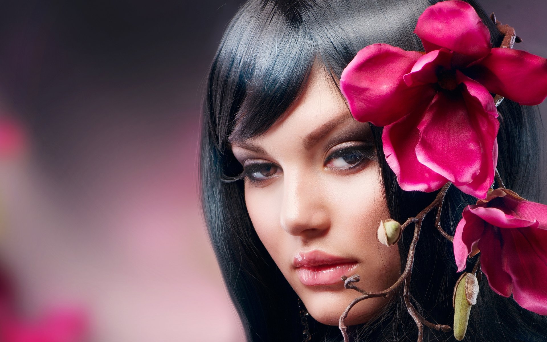 A striking HD wallpaper featuring a woman, Judy Wilkins, with long black hair and a vibrant pink flower, set against a soft, blended background.
