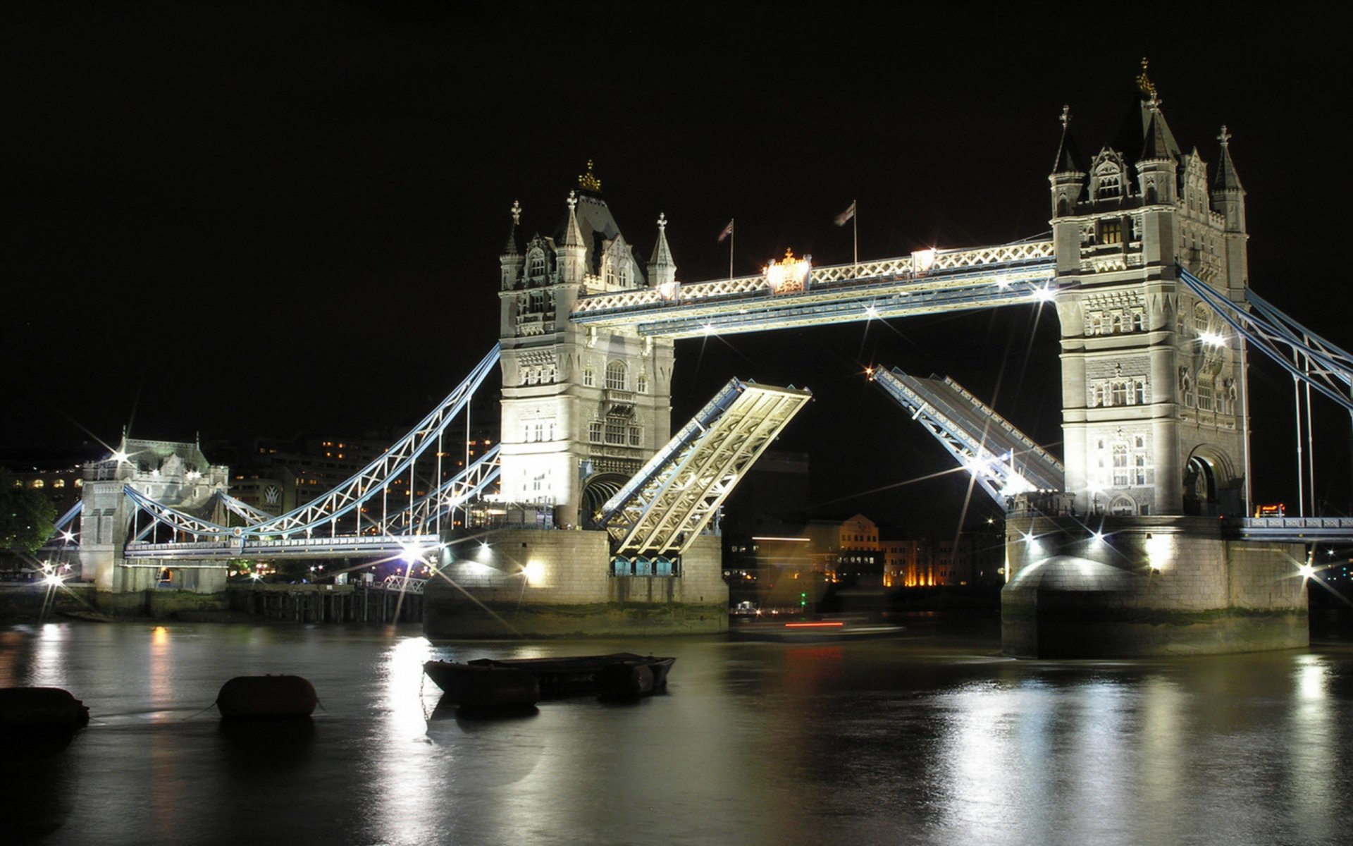 A stunning night view of London’s Tower Bridge, beautifully illuminated against the dark sky, showcasing the iconic man-made structure reflecting on the water below.