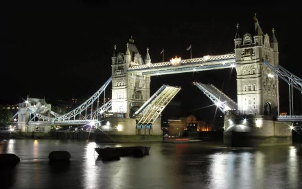 A stunning night view of London’s Tower Bridge, beautifully illuminated against the dark sky, showcasing the iconic man-made structure reflecting on the water below.