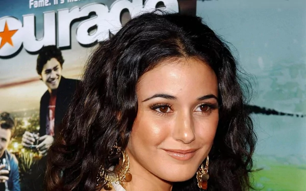 HD PC desktop wallpaper featuring celebrity Emmanuelle Chriqui smiling with curly dark hair, wearing gold earrings against a promotional backdrop.