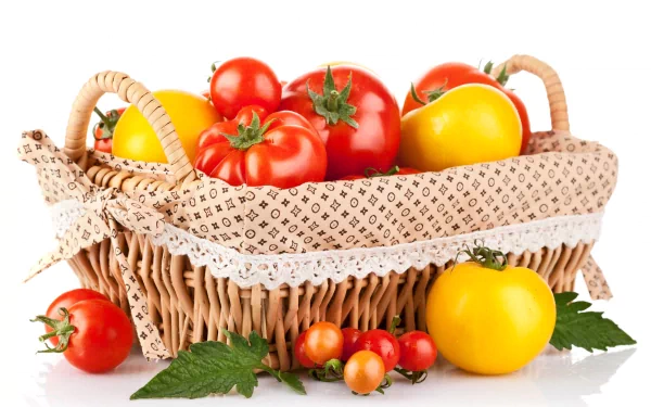 A wicker basket filled with ripe red and yellow tomatoes, surrounded by green leaves, captured in 4K Ultra HD as a vibrant PC desktop wallpaper.