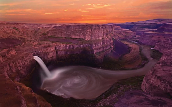 A stunning view of Palouse Falls in Washington, showcasing a majestic waterfall cascading into a serene river, surrounded by dramatic canyon landscapes at sunset.