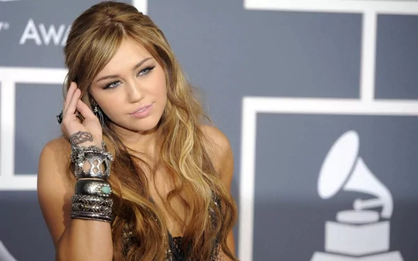 HD PC desktop wallpaper of a female pop singer at a music awards backdrop, long wavy hair and stacked bracelets, posing thoughtfully as a music-themed celebrity portrait.