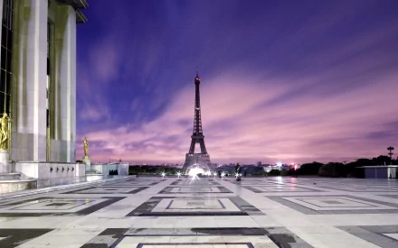 The HD wallpaper features a stunning view of the Eiffel Tower in Paris, France. The man-made structure stands tall against a vibrant, colorful sky, creating a picturesque background.