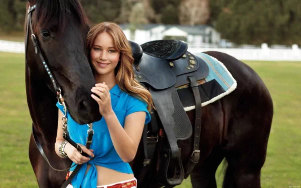 Jennifer Lawrence standing next to a black horse in a green field. This HD wallpaper captures the serene connection between the actress and the horse, providing a beautiful background image.