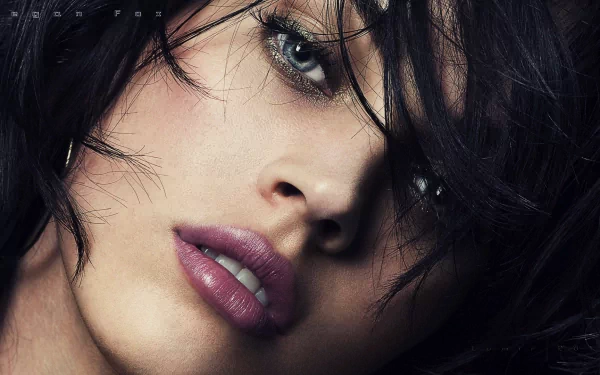 A striking HD desktop wallpaper featuring Megan Fox, showcasing her captivating gaze and soft features, framed by her tousled dark hair.