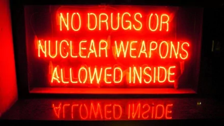 HD PC desktop wallpaper featuring a glowing red neon sign reading NO DRUGS OR NUCLEAR WEAPONS ALLOWED INSIDE, reflected on a dark surface.