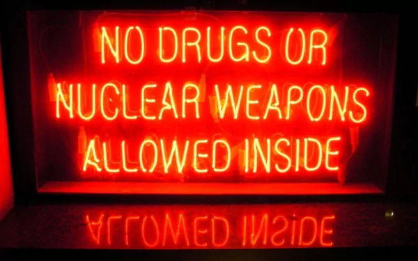 HD PC desktop wallpaper featuring a glowing red neon sign reading NO DRUGS OR NUCLEAR WEAPONS ALLOWED INSIDE, reflected on a dark surface.