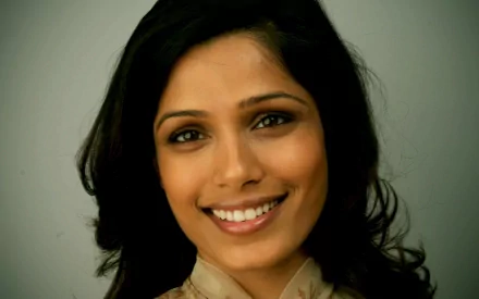 A close-up of Freida Pinto smiling warmly, showcasing her beautiful features and flowing hair, serves as an engaging HD desktop wallpaper and background.