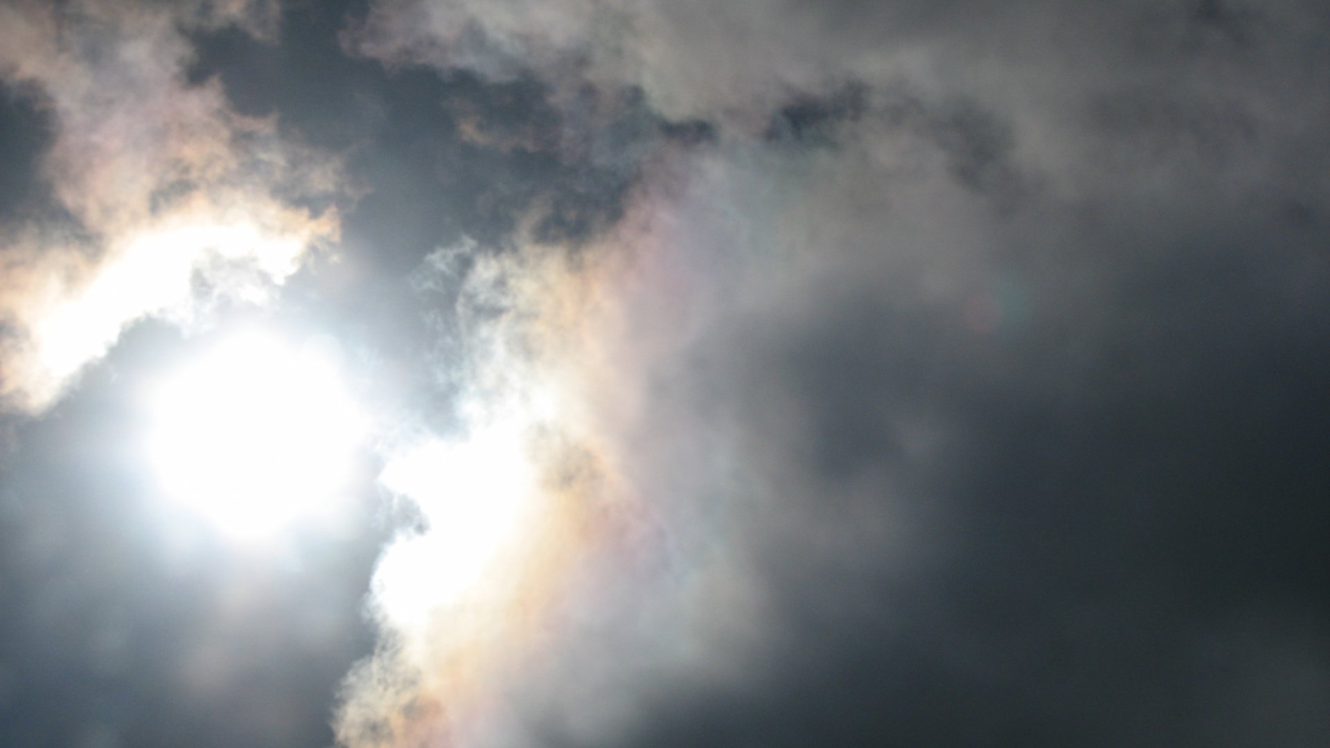 2K Quad HD PC desktop wallpaper: bright sun piercing swirling clouds in a dramatic sky — nature-themed cloud and sky background.