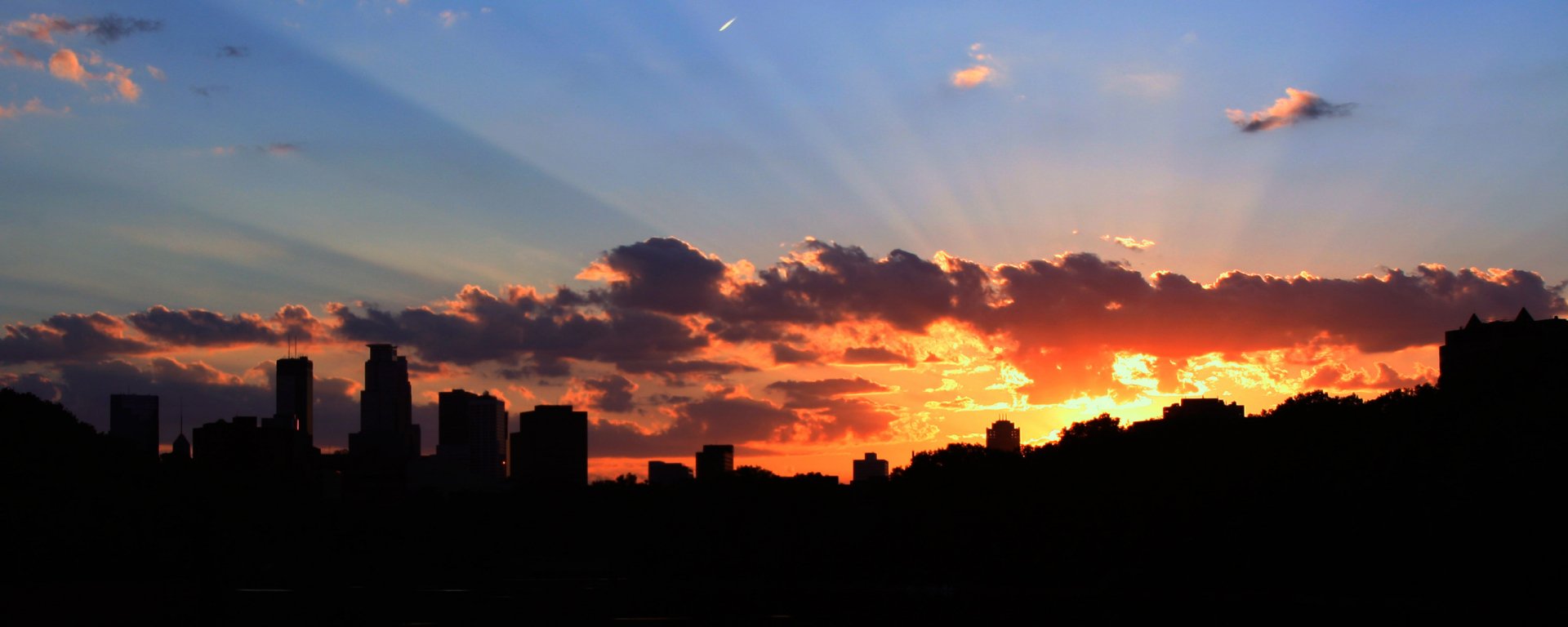 HD desktop wallpaper showcasing a vibrant sunset over the man-made skyline of Minneapolis with dramatic clouds and radiant sky colors.