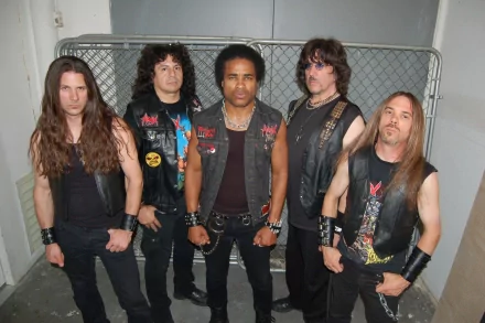 Five members of a heavy metal band pose against a chain-link fence, embodying the spirit of iconic groups like Exodus, Megadeth, and Metallica. A striking HD desktop wallpaper for music fans.