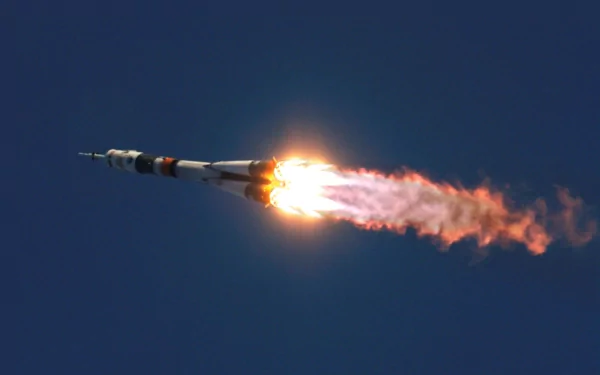 HD desktop wallpaper featuring a man-made rocket launching into the clear blue sky, with bright flames and exhaust trailing behind it.