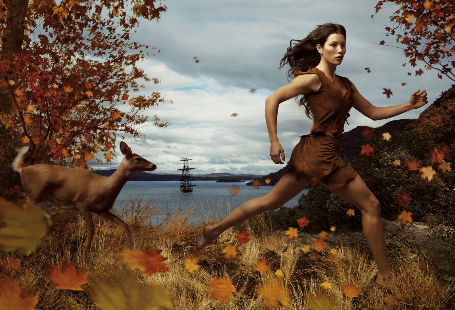 Jessica Biel runs through a vibrant autumn landscape alongside a deer, with a ship visible in the background. This enchanting image is part of the Disney Dream Portraits collection.