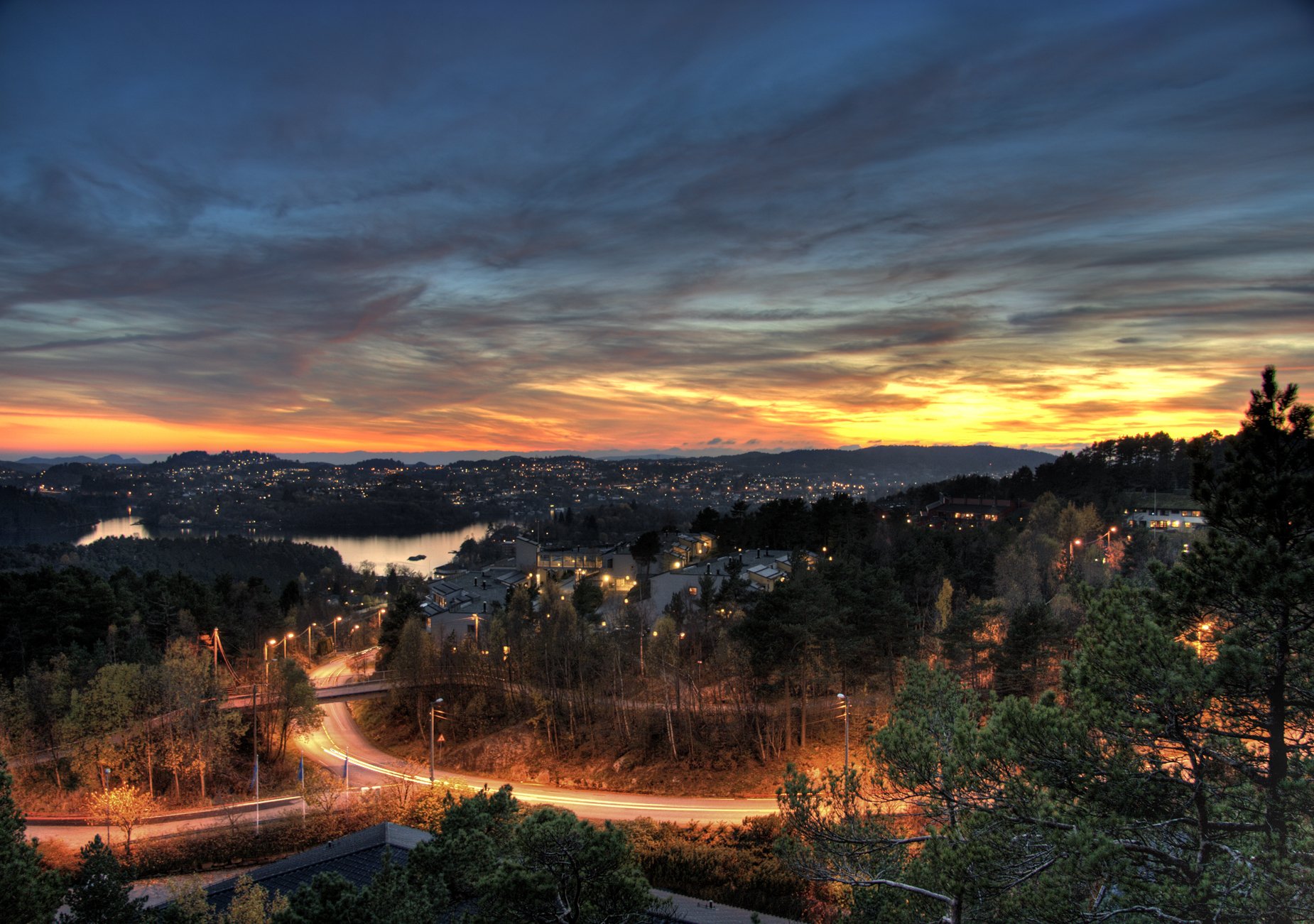 HD desktop wallpaper of a man-made cityscape at dusk with winding roads, illuminated buildings, and a colorful sky.