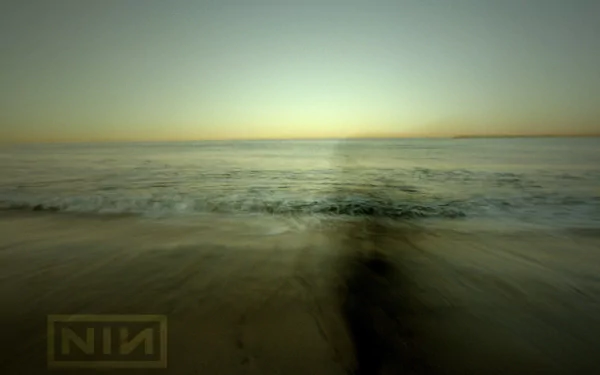 A serene HD desktop wallpaper featuring a tranquil ocean scene at sunset, subtly branded with the Nine Inch Nails logo. The calming colors create a reflective atmosphere.