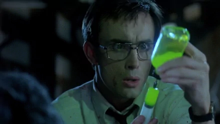 HD desktop wallpaper from the movie Re-Animator, featuring a man in glasses holding a glowing green vial.