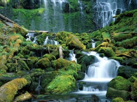 HD desktop wallpaper featuring a serene nature scene with a cascading waterfall flowing over moss-covered rocks.