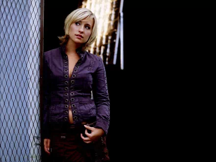 A close-up image of Allison Mack, featuring her in a stylish jacket, standing against a dark background. This HD wallpaper captures a thoughtful moment.