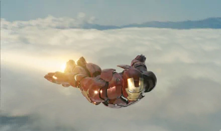 HD desktop wallpaper featuring Iron Man soaring above the clouds with mountains in the background. The iconic suit is illuminated, showcasing the character's flight amidst a serene, high-altitude setting.