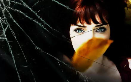 HD desktop wallpaper featuring celebrity Susan Coffey with striking blue eyes and a leaf partially covering her face against a dark, cracked-glass background.