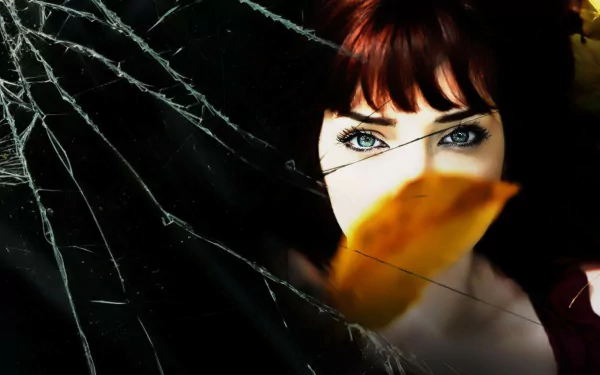 HD desktop wallpaper featuring celebrity Susan Coffey with striking blue eyes and a leaf partially covering her face against a dark, cracked-glass background.