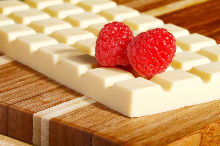 HD wallpaper of two raspberries on a white chocolate bar, set on a wooden surface — a vivid and appetizing background.
