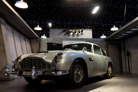 HD PC desktop wallpaper featuring a classic silver Aston Martin DB5 parked indoors under star-like ceiling lights.