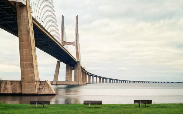 HD desktop wallpaper showcasing the man-made Vasco da Gama Bridge stretching over calm water beneath a cloudy sky.