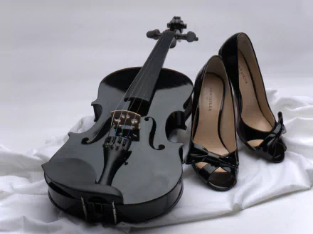 HD desktop wallpaper featuring a stylish black violin next to elegant high-heeled shoes, arranged on a soft white background, symbolizing the fusion of music and fashion.