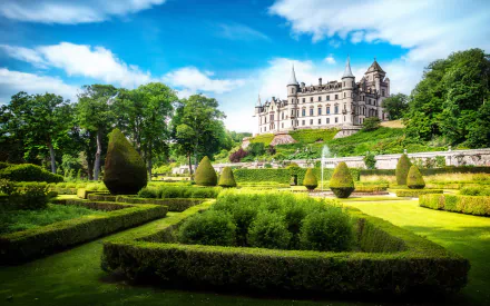 A stunning view of Dunrobin Castle, showcasing its grand architecture against a vibrant sky, surrounded by meticulously manicured gardens. An impressive HD desktop wallpaper.