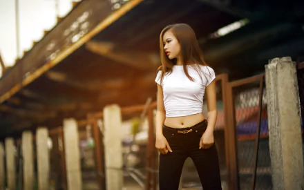 An Asian woman standing confidently by a fence under a bridge, captured in a high-definition image suitable as a desktop wallpaper.