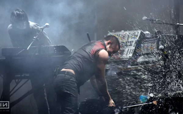 A dynamic live performance featuring Nine Inch Nails, with musicians engaged in an energetic act amidst dramatic lighting and splashes, set as a HD desktop wallpaper.