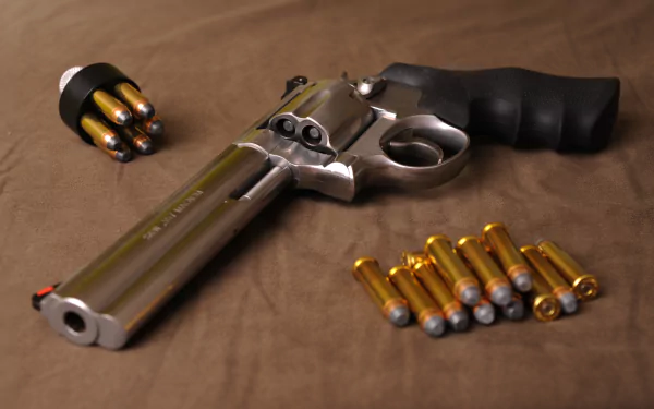 A high-definition desktop wallpaper featuring a Smith & Wesson revolver, surrounded by bullets and a speedloader on a neutral background.