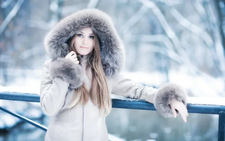 A woman model in a fur-trimmed coat poses outdoors in a snowy winter scene, making for an elegant HD desktop wallpaper and background.