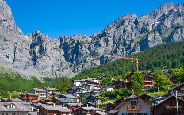 A scenic view of a village nestled among majestic mountains in Montreux, Switzerland, showcasing a blend of nature and man-made structures against a clear blue sky.