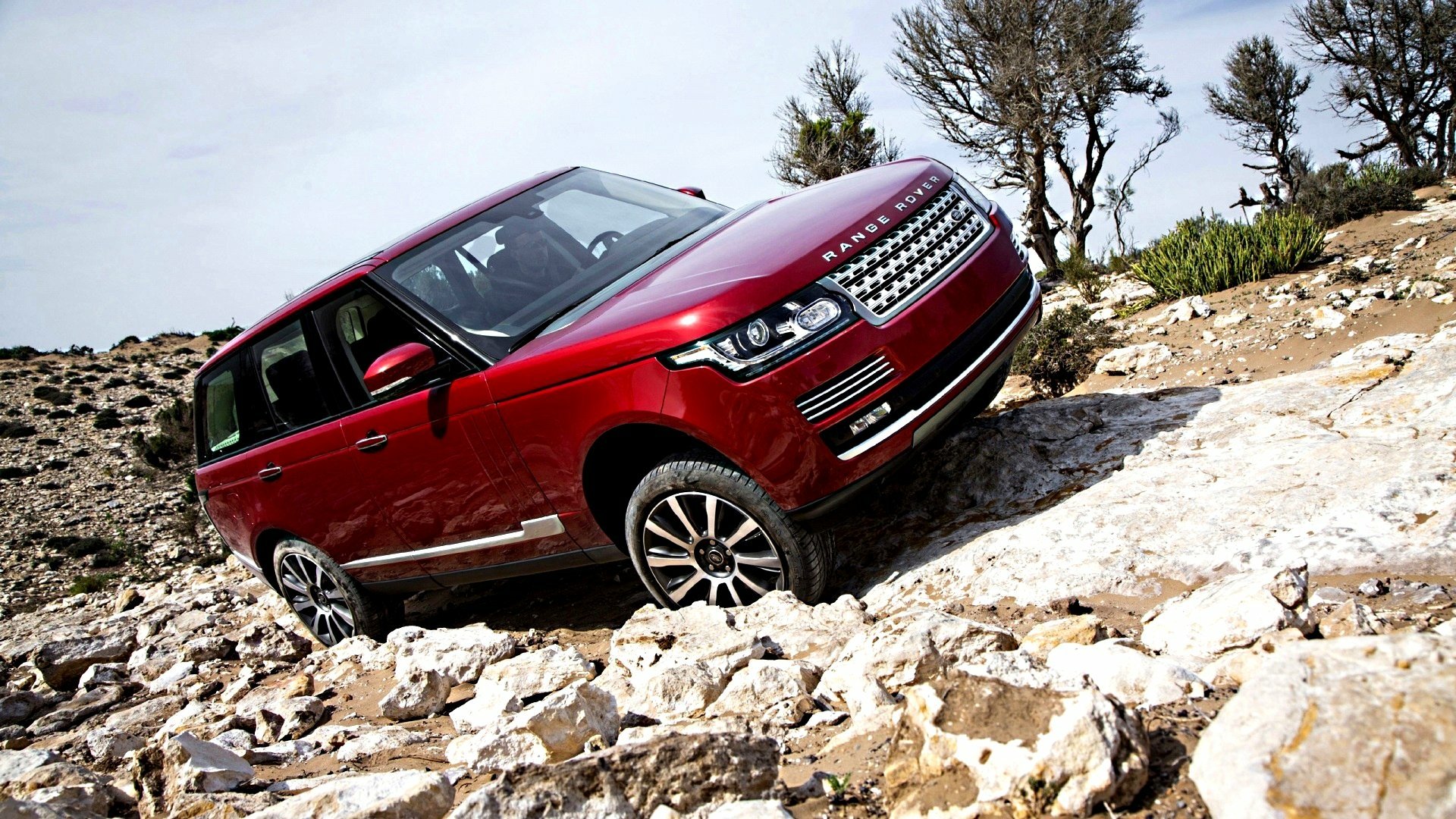 HD PC desktop wallpaper featuring a red Range Rover navigating rocky terrain, showcasing the vehicle’s off-road capability and rugged design.