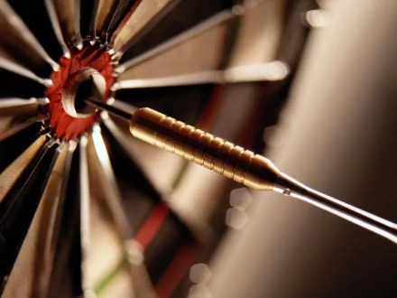 Close-up of a dart embedded in a dartboard, showcasing the intricate details of the dart's tip and the board's segments, creating a dynamic HD desktop background.