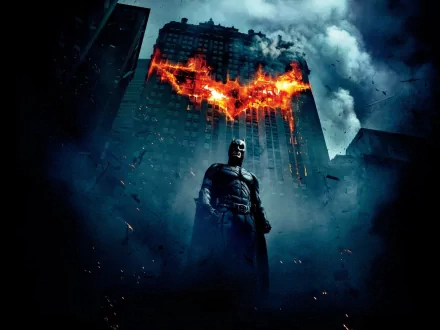 HD wallpaper featuring Batman from the movie The Dark Knight, standing in front of a skyscraper with a flaming bat symbol and dark storm clouds in the background.