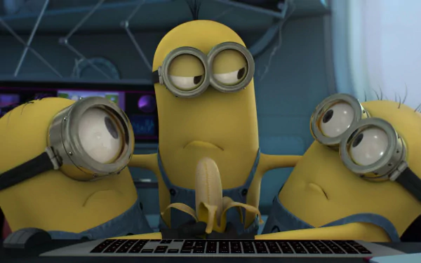 Three animated Minions from Despicable Me 2 are gathered around a keyboard, expressing curiosity and mischief. This vibrant image serves as a fun HD desktop wallpaper.