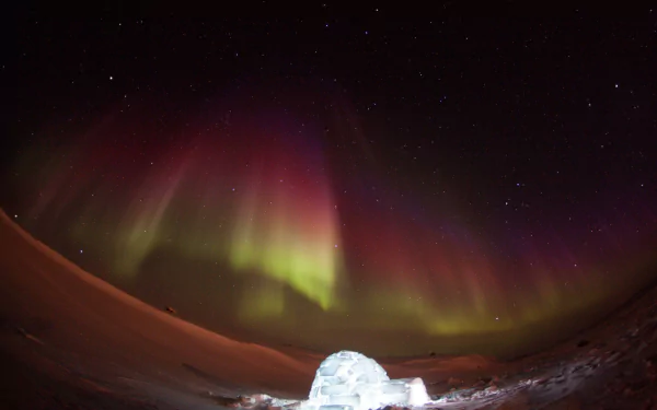 Vibrant aurora borealis glows in a dark night sky above a glowing igloo, capturing the colorful beauty of nature in this HD desktop wallpaper.