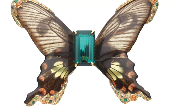 Man-made jewelry: butterfly-shaped brooch with translucent patterned wings and central emerald-cut gemstone, presented as a 2K Quad HD PC desktop wallpaper/background.