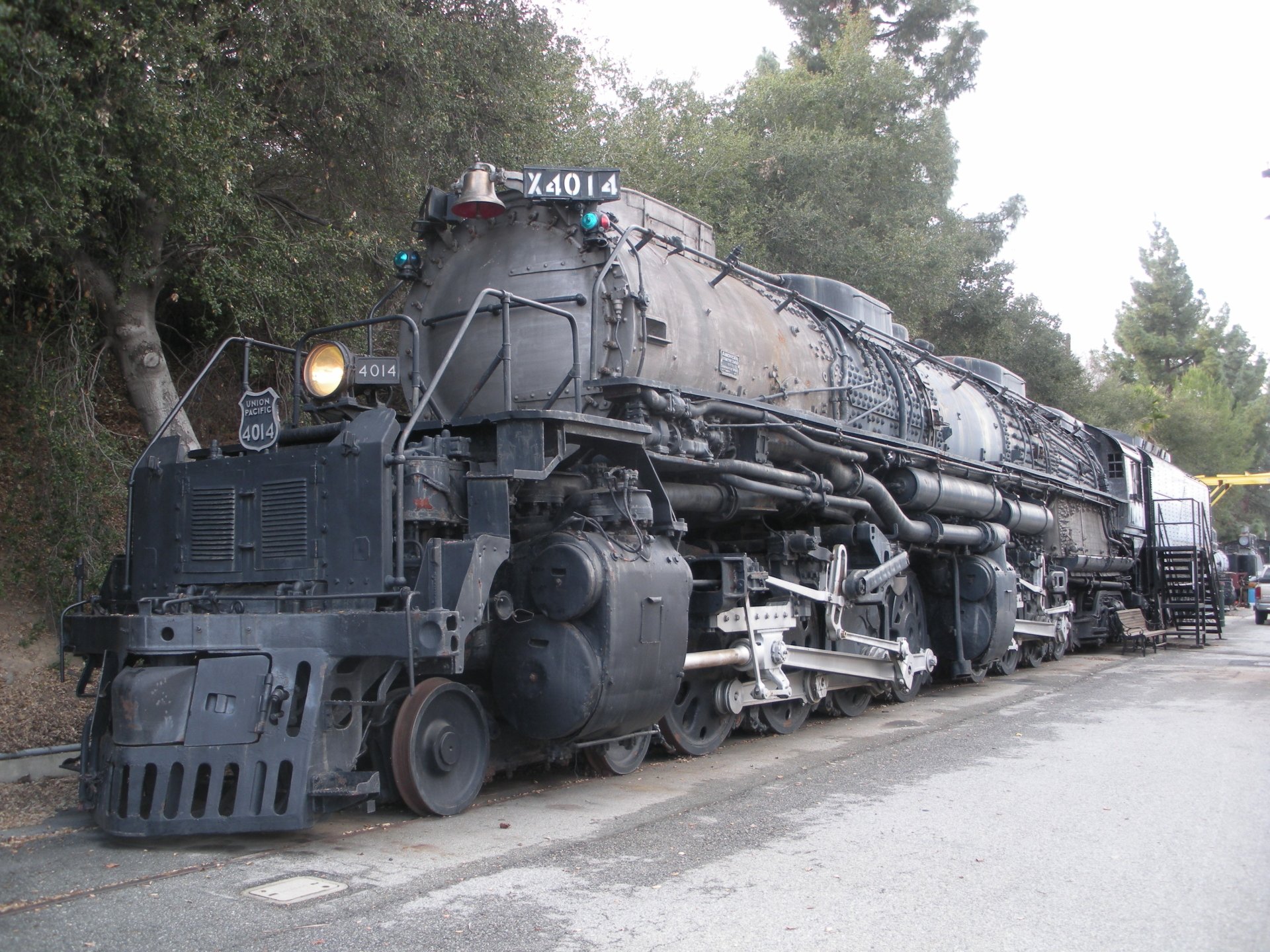 A vintage steam train with a rugged exterior rests along a tree-lined path, captured in high definition for an impressive PC desktop wallpaper and background.