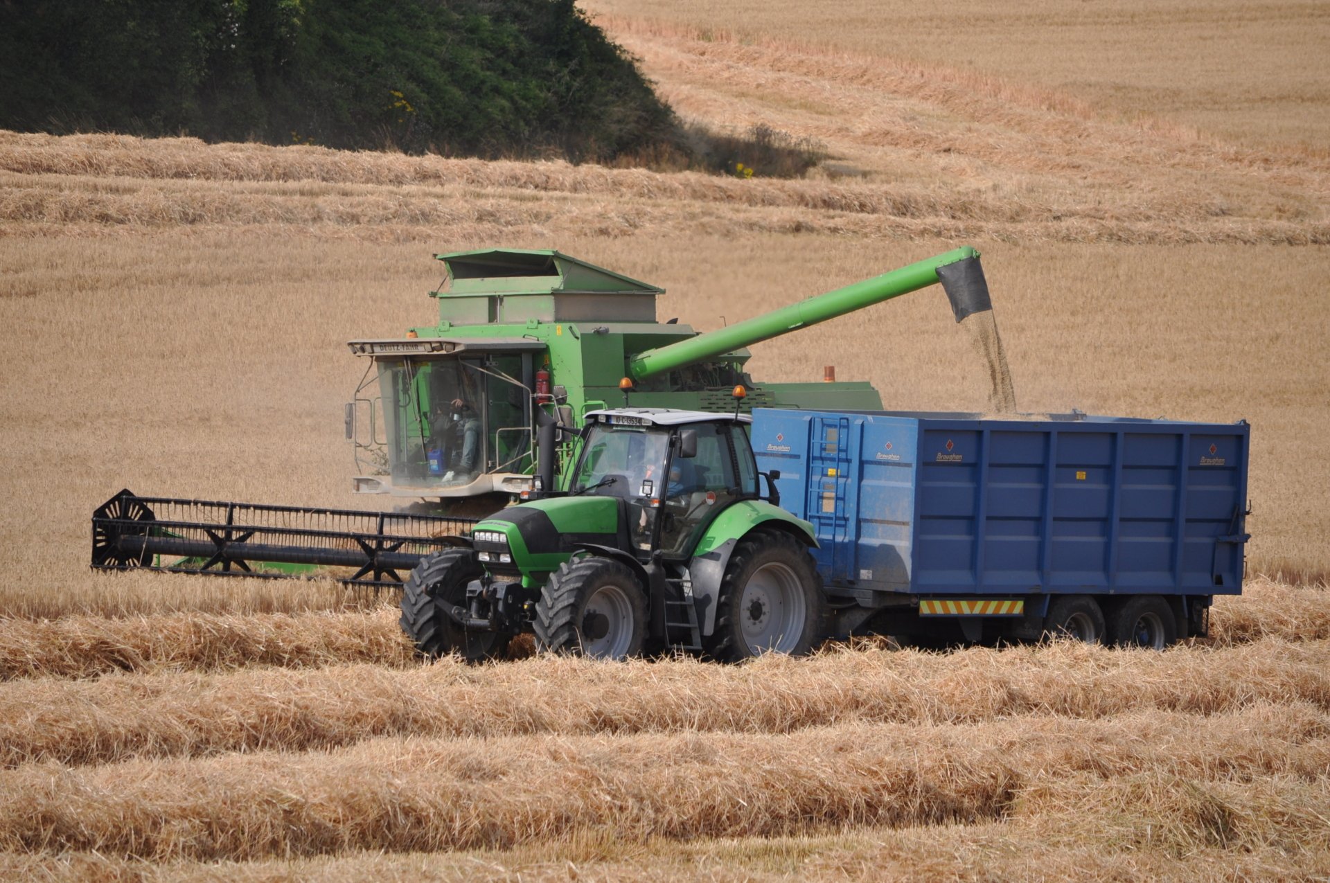 HD PC desktop wallpaper showing a Deutz-Fahr tractor and combine harvester working in a golden wheat field during harvest.
