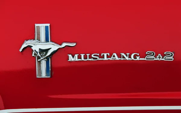 Close-up of a Ford Mustang 2+2 emblem on a red vehicle, captured in 4K Ultra HD for a PC desktop wallpaper and background.