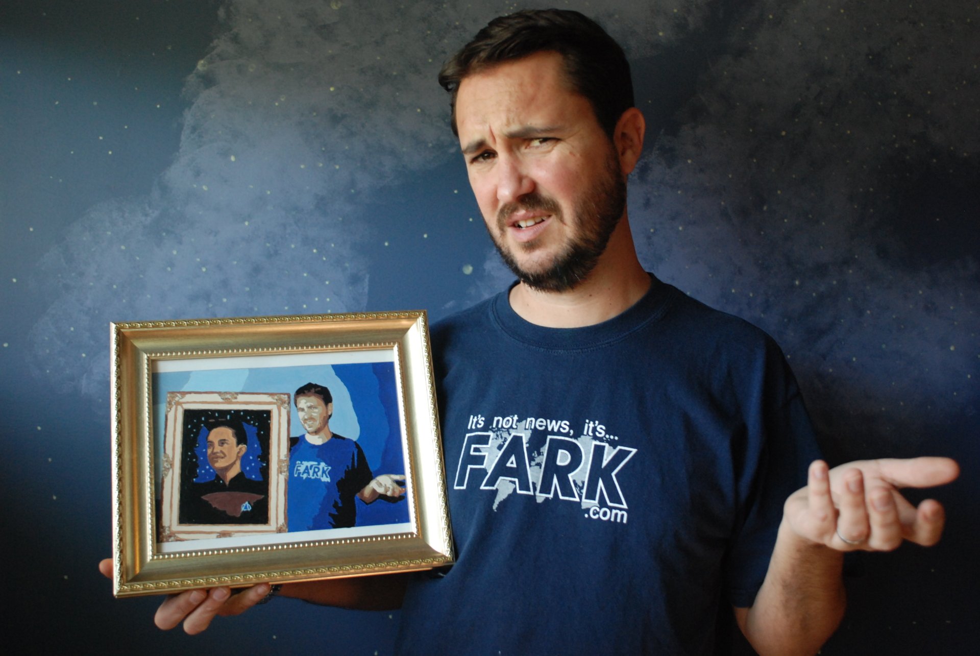 HD wallpaper with a man holding a framed picture, appearing puzzled, against a starry background.