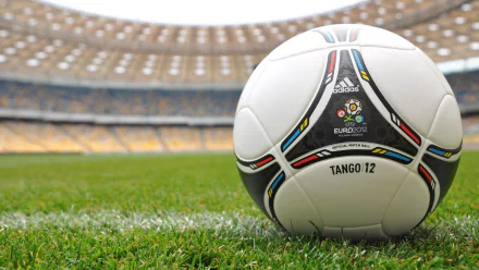 HD desktop wallpaper featuring an Adidas Tango 12 soccer ball on the grass inside a stadium, representing UEFA Euro 2012 and the spirit of sports.