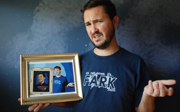 HD wallpaper with a man holding a framed picture, appearing puzzled, against a starry background.