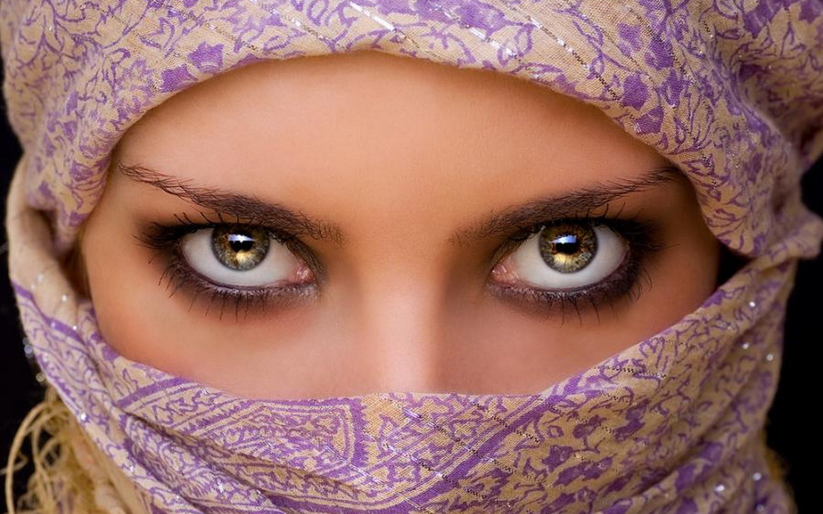A captivating close-up of a woman's eyes, framed by a beautifully patterned scarf, showcasing intricate details and vibrant colors. This image serves as an HD desktop wallpaper and background.