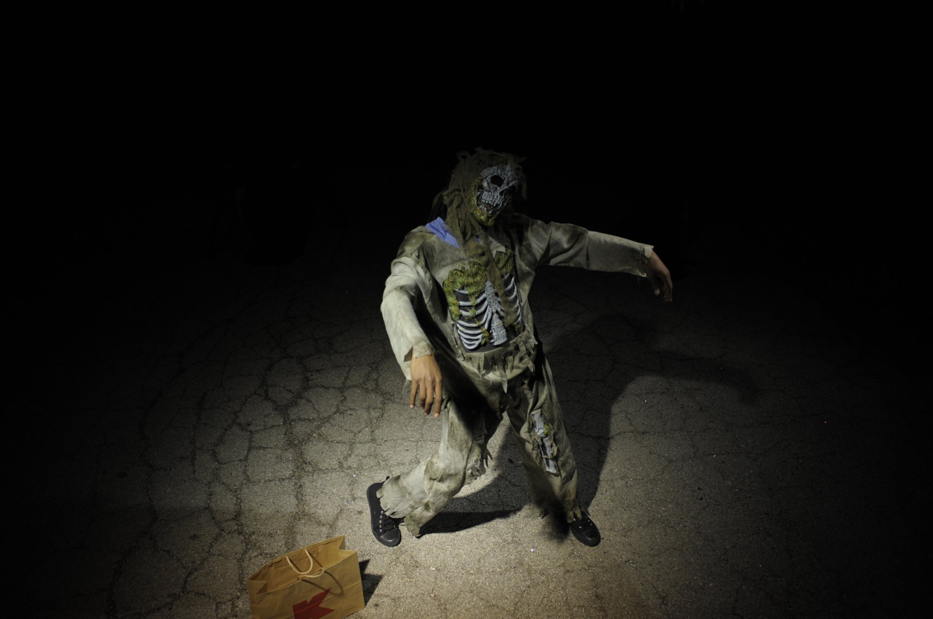 A 4K Ultra HD Halloween-themed PC desktop wallpaper depicting a person in a zombie costume crawling on a cracked surface with dark, eerie lighting.